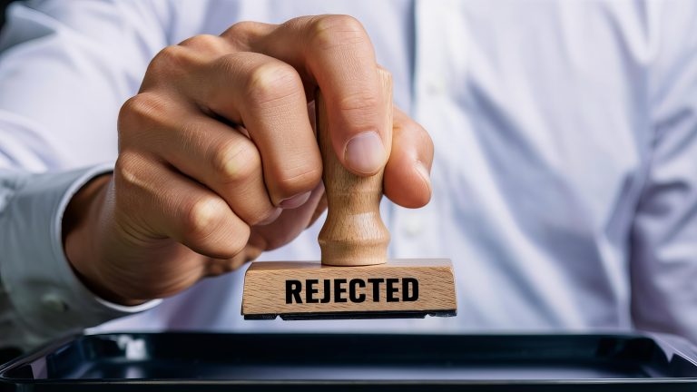 Hand Holding Rubber Stamp that says Rejected
